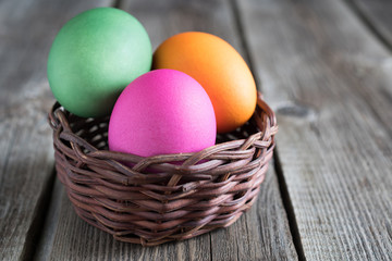 Obraz na płótnie Canvas Easter eggs in basket on a wooden 
