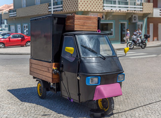 Naklejka premium Black three-wheeled light commercial vehicle at the city street