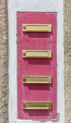 Golden mailboxes on a wall painted pink