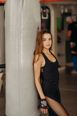 Naklejka premium Woman boxer training hard. Young adult woman doing kickboxing training in gym.