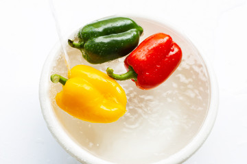 Bell pepper soaked in water. Washing fresh vegetables on white