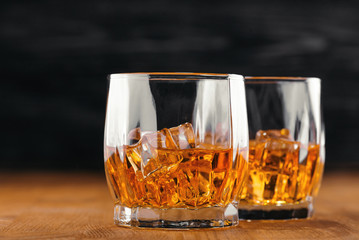 Two glasses of whiskey. On the wooden background