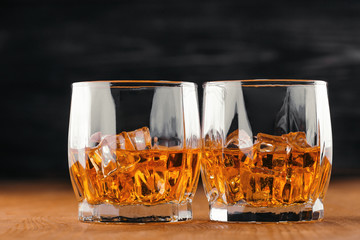 Two glasses of whiskey. On the wooden background