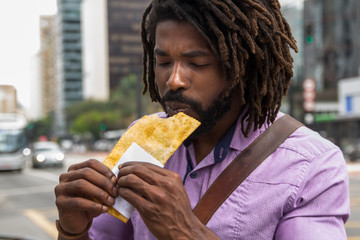 African american man  tasting brazilian snack known as Pastel - asian recipe.