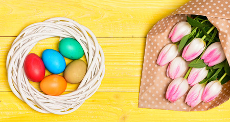 Obraz na płótnie Canvas Spring holiday. Tradition celebrate easter. Happy easter season. Easter eggs symbol. Spring vibes. Easter is coming. Colorful bright eggs and bouquet fresh tulip flowers on yellow background top view