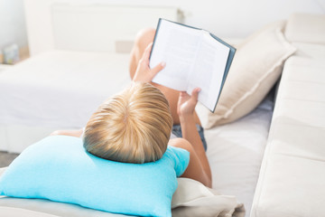 Young woman reading a book on sofa