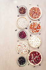 Assortment of beans on a stone background. Crimson cranberry, red, painted pony, black turtle, brown, black-eyed, Jacob's Cattle (heirloom) and lima, top view.