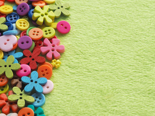 many buttons of different shapes, colors and sizes on plush fabric of light green color. copy space..