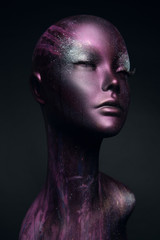Closeup studio shot of violet woman mannequin with stylish makeup, dark background