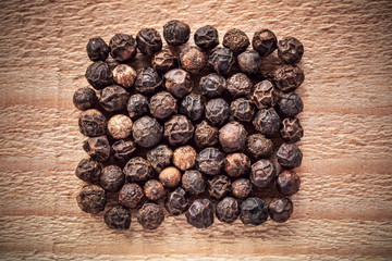 Black peppercorn closeup on wooden surface
