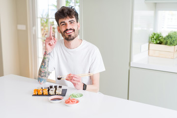 Young man eating asian sushi from home delivery surprised with an idea or question pointing finger with happy face, number one
