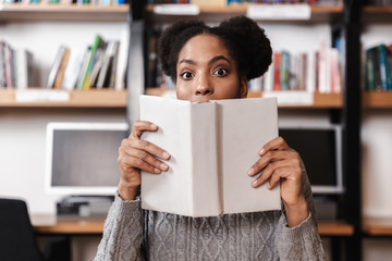 Happy young student girl studying at the library