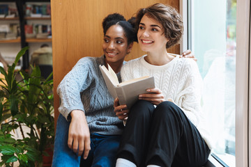 Two cheerful young girls students studying