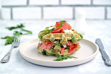Light dinner, lunch or lunch, savory spinach snack waffles with salted salmon and cream cheese on a ceramic plate