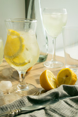 Summer refreshing drink of fresh lemon and ice cubes in transparent glass a light background. Homemade mahito or detox.