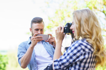 Man and woman taking photos with a camera and a smartphone.