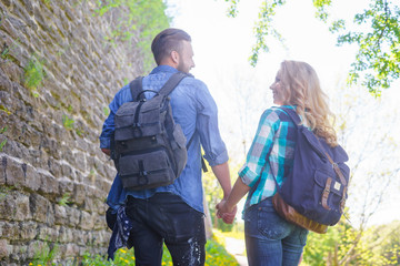 Young travelers walking in a park. Man and woman having vacation. Backpackers, traveling and tourism.