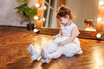 Easter celebration, pet care and animals concept. Cute happy little girl sitting on floor, holding...