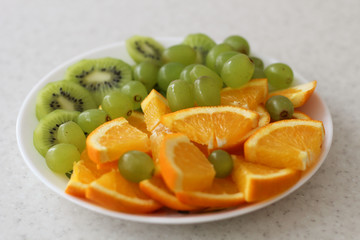 white fruit plate with grapes, orange, kiwi