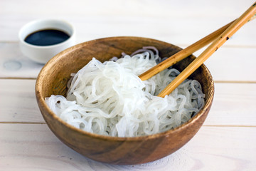 Chinese dietary shirataki konjak  and soy sauce in a wooden bowl on a white background. Dietary noodles for weight loss. Background about chinese food