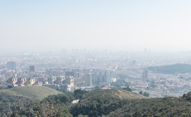 Overview of the polluted city of Barcelona, from the Collserola mountain, with a layer of smog over it.