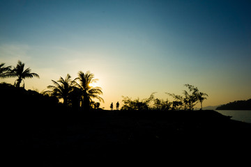 Fototapeta na wymiar Scenery of sunset, forest of island and traveler silhouette