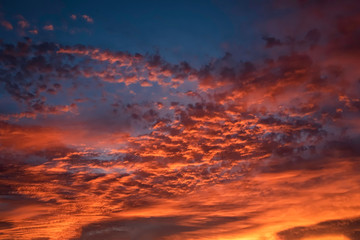 A majestic and awe-inspiration combination of deep blue sky and fiery orange and yellow clouds at sunset.