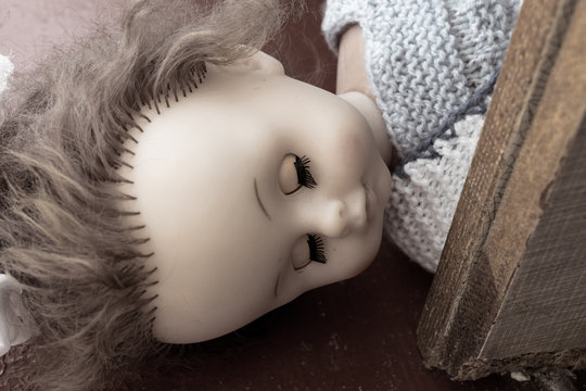 Scary doll lies with a closed eyes