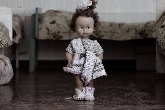 The doll stands between the beds in the bedroom of the orphanage