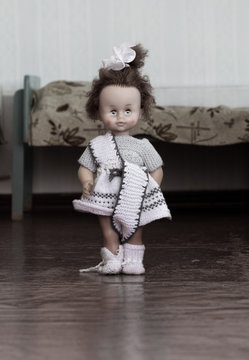 The doll stands between the beds in the bedroom of the orphanage