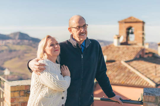 Hugging Senior Couple In Vacation, Visiting Old Italian Town.