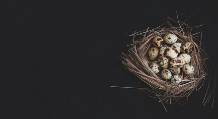 Quail eggs stacked in a pile or pyramid in a nest on a black backgroundMockup for the Easter holiday. Close up