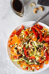 Asian coleslaw salad with white cabbage, carrot, pepper, sesame and cashew nuts. Healthy food concept. Light concrete background. Copy space.
