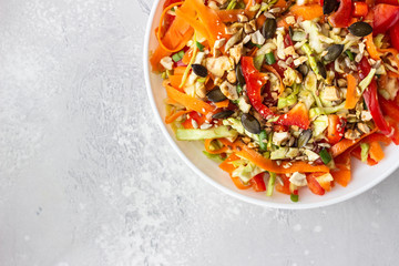Asian coleslaw salad with white cabbage, carrot, pepper, sesame and cashew nuts. Healthy food concept. Light concrete background. Copy space.