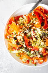 Asian coleslaw salad with white cabbage, carrot, pepper, sesame and cashew nuts. Healthy food concept. Light concrete background. Copy space.