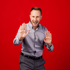 man making stop gesture over red background. emotion and people concept