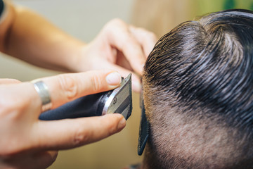 Fototapeta premium A professional hairdresser makes the design of the head, shave your head electric razor. Beauty shop. Male beauty. 