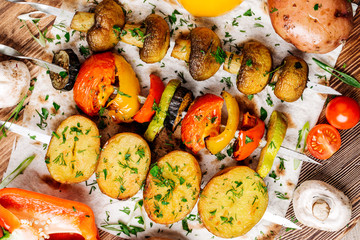 Variety of BBQ grilled vegetables lunch. skewers with  potatoes, tomatoes, mushrooms, eggplants, zucchinis  on  wood background.