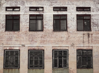 The windows of an old abandoned clinic. The facade of an old brick building.