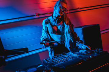 attractive blonde dj woman holding bottle while touching vinyl record
