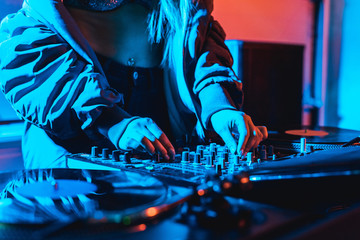 cropped view of dj woman touching dj mixer in while standing in nightclub