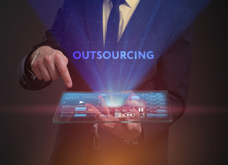 The concept of business, technology, the Internet and the network. A young entrepreneur working on a virtual screen of the future and sees the inscription: Outsourcing