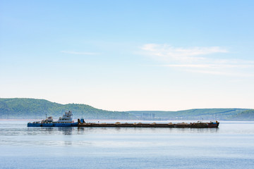 Obraz premium Old cargo barge transporting gravel. On the background of beautiful mountains.