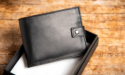 Black leather wallet on a wooden table - obrazy, fototapety, plakaty