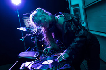 attractive blonde dj girl touching vinyl record in nightclub