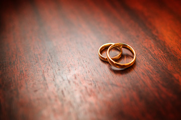 Details of the morning of the wedding day. two gold wedding rings are on the brown wood table