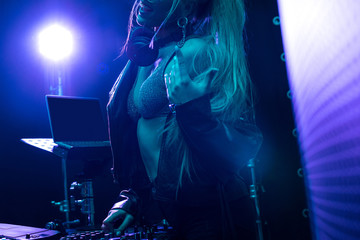 cropped view of blonde dj girl standing near dj mixer in nightclub