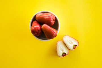 Syzygium Aqueum , Bell fruit or Jambu Air in local Malay language, is a fruit that has a shape like a bell; shot on isolated yellow background.