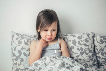  The little girl caught a cold. The girl lies in bed and is ill. The child has a runny nose and cough. 