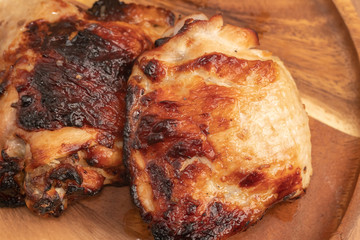 close up of grilled chiken on wooden plate